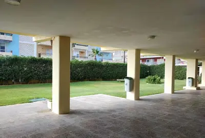 a covered area with columns and a park with grass at Modern Apartment Frontline Beach in Mareny Blau