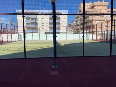 a tennis court seen through a glass door at Excelente ático con gran terraza y barbacoa en Canet d'en Berenguer in Valencia
