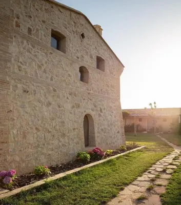 a stone building with flowers in front of it at Hotel Rural El Teular in Sueca