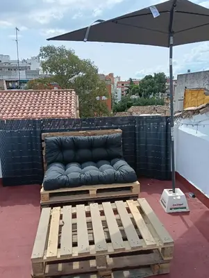 a couch sitting on a deck under an umbrella at El Molino Buñol Apartamento in Buñol
