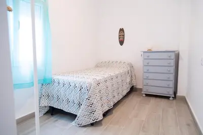 a small bedroom with a bed and a dresser at El hogar del mar. in Sueca