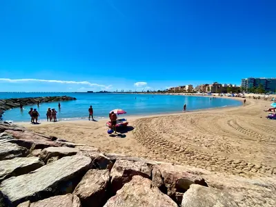 a group of people walking on a beach at Bonita Planta baja con patio en 1ª línea de playa in Puerto de Sagunto