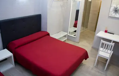 a bedroom with a red bed and a mirror at Pensión Jamaica in Valencia