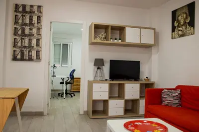 a living room with a red couch and a television at Precioso apartamento en Malvarrosa Playa Valencia in Valencia