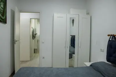 a bedroom with white walls and a bed and a mirror at Precioso apartamento en Malvarrosa Playa Valencia in Valencia