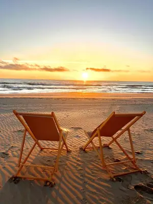 two beach chairs sitting on the beach at sunset at El Bikini Cullera - Junto a la playa - Right on the beach in Cullera