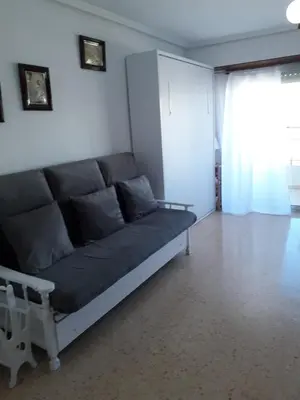 a couch in a living room with a window at Apartamento Cullera a 200 metros playa San Antonio con parking in Cullera