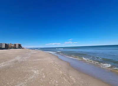 a beach with the ocean and buildings in the background at Apartamento en primera línea, Les Palmeretes in Sueca