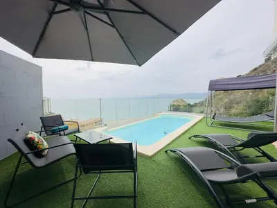a swimming pool with chairs and an umbrella at Beautiful villa spectacular sea view in Faro de Cullera