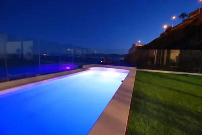 a swimming pool at night with blue lights at Beautiful villa spectacular sea view in Faro de Cullera