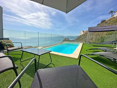 a house with a swimming pool with chairs and a table at Beautiful villa spectacular sea view in Faro de Cullera