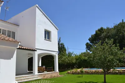 a white house with a tree and a yard at Gran Chalet con Piscina (8-10 pp) in La Eliana