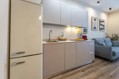 a kitchen with white cabinets and a blue couch at Pivote Flats - Marina B in Valencia