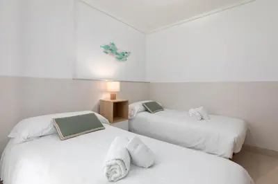 two twin beds in a room with white walls at ApartUP Patacona Paradise Duplex in Valencia