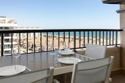 a table with chairs and wine glasses on a balcony at ApartUP Patacona Paradise Duplex in Valencia
