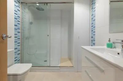 a white bathroom with a shower and a sink at ApartUP Patacona Paradise Duplex in Valencia
