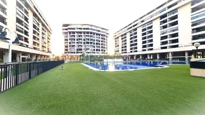 a green field in the middle of two buildings at BEACH VALENCIA LUXURY D9-29 Apartment with terrace and sea views with two rooms in Valencia
