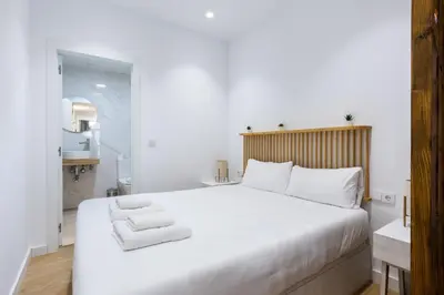 a bedroom with a large white bed and a bathroom at VLC HOST - San Jacinto in Valencia