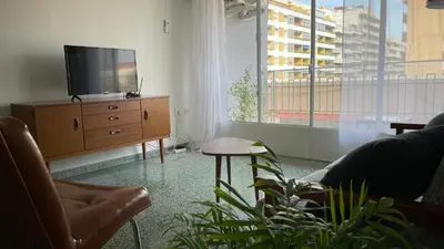 a living room with a tv on a wooden dresser at Luminoso piso cerca de la playa in Cullera