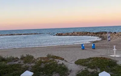 a beach with two blue trash cans and the ocean at 1era linea de playa VILLA SALES Cullera Marenyet in Cullera
