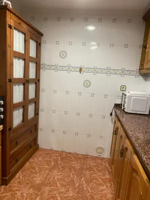 a kitchen with white tiled walls and a microwave at 1era linea de playa VILLA SALES Cullera Marenyet in Cullera
