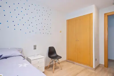 a bedroom with a bed and a black chair at Cómodo y luminoso apto cerca de Playas y Valencia in Sueca
