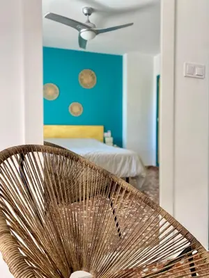 a rattan chair in a bedroom with a blue wall at Mi Oasis Azul Parking, AC, Fibra, VT-54949-V in Sueca