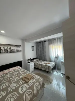 a bedroom with two beds and a window with curtains at precioso apartamento a 10 metros de la playa in Cullera