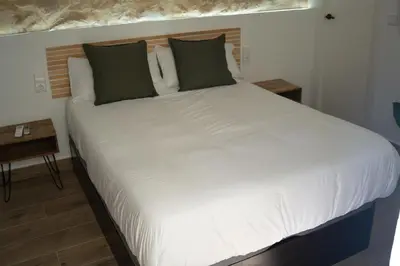 a large bed with white sheets and green pillows at Hotel Boutique - Estancia dos Olivos in Quesa