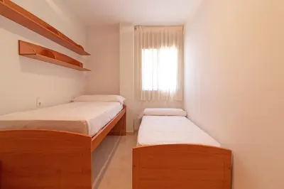 two beds in a small room with a window at Global Vacacional, Apartamento con terraza de 70m y piscina en Canet de Berenguer in Canet de Berenguer