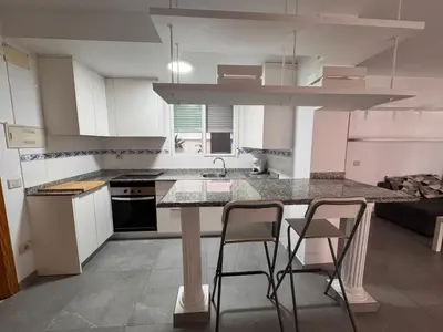 a kitchen with a island with three bar stools at Apto 3 habitaciones, vistas al mar Moncofar Grao in Moncófar