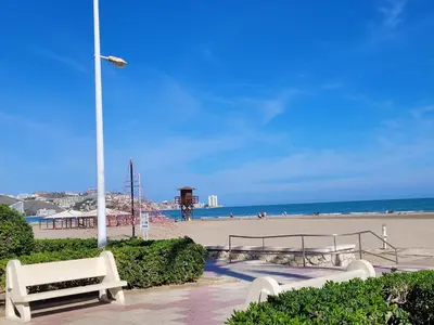 a beach with benches and a street light and a beach at TIGA muy cerca de la plaza de San Antonio in Cullera