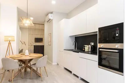 a kitchen with white cabinets and a table and chairs at Favara Suites A by Concept Flats in Valencia