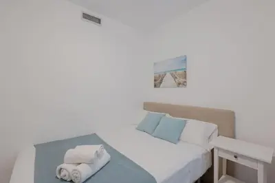 a white bedroom with a bed with towels on it at Apartamento playa Patacona con parking in Valencia