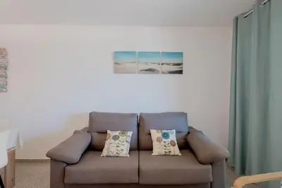 a brown couch with pillows in a living room at Apartamento playa Patacona con parking in Valencia