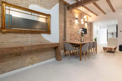 a dining room with a table and a mirror on a brick wall at My Loft 4 You Patraix Style in Valencia