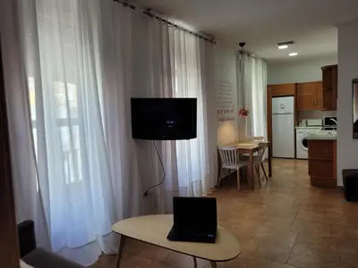 a living room with a laptop on a table and a kitchen at Living Valencia Apartments - Merced in Valencia