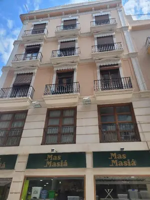 a tall building with windows and a mas masia sign on it at Living Valencia Apartments - Merced in Valencia