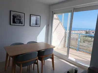 a dining room with a table and chairs and a large window at Beach,s House in Playa del Puig in La Torre