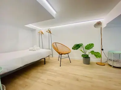 a white bedroom with a bed and a chair at Beach Flat for Family & Groups in Valencia