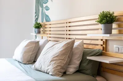 a bed with white pillows and a wooden headboard at Mestalla Apartment Ideal for Mid-Term Stays in Valencia