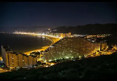 a view of a hotel and a beach at night at Acogedor Apartamento Cullera 200 metros playa in Cullera