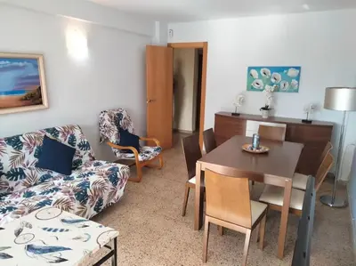 a living room with a couch and a table and chairs at Acogedor Apartamento Cullera 200 metros playa in Cullera
