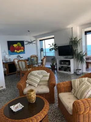 a living room with wicker furniture and a television at A modern House with Perfect Views in Mareny Blau