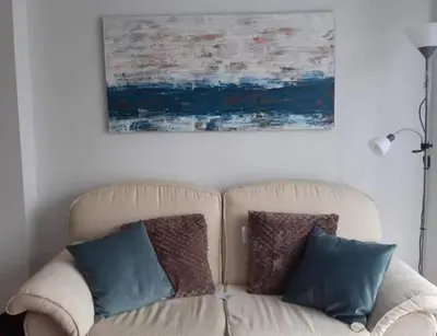 a couch with two pillows sitting under a painting at El balcón de Alexia, 5 minutos del aeropuerto in Partida de La Cañada