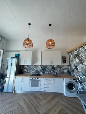 a kitchen with white cabinets and a sink and two lights at Garage House in Calles