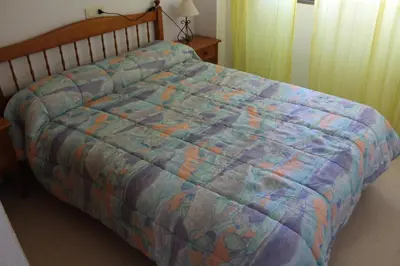 a bed with a colorful comforter in a bedroom at Jardin II Solo Familias Serviplaya in Playa de Xeraco