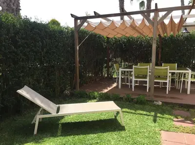 a patio with a table and chairs and a bench at Agradable adosado con piscina y jardín in Canet de Berenguer