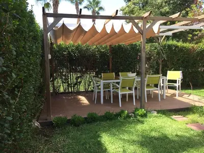 a wooden deck with a table and chairs under a pergola at Agradable adosado con piscina y jardín in Canet de Berenguer