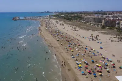 a crowd of people on a beach with umbrellas at Agradable adosado con piscina y jardín in Canet de Berenguer